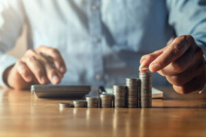Calculating capital needed to start business. There is calculator, coins.